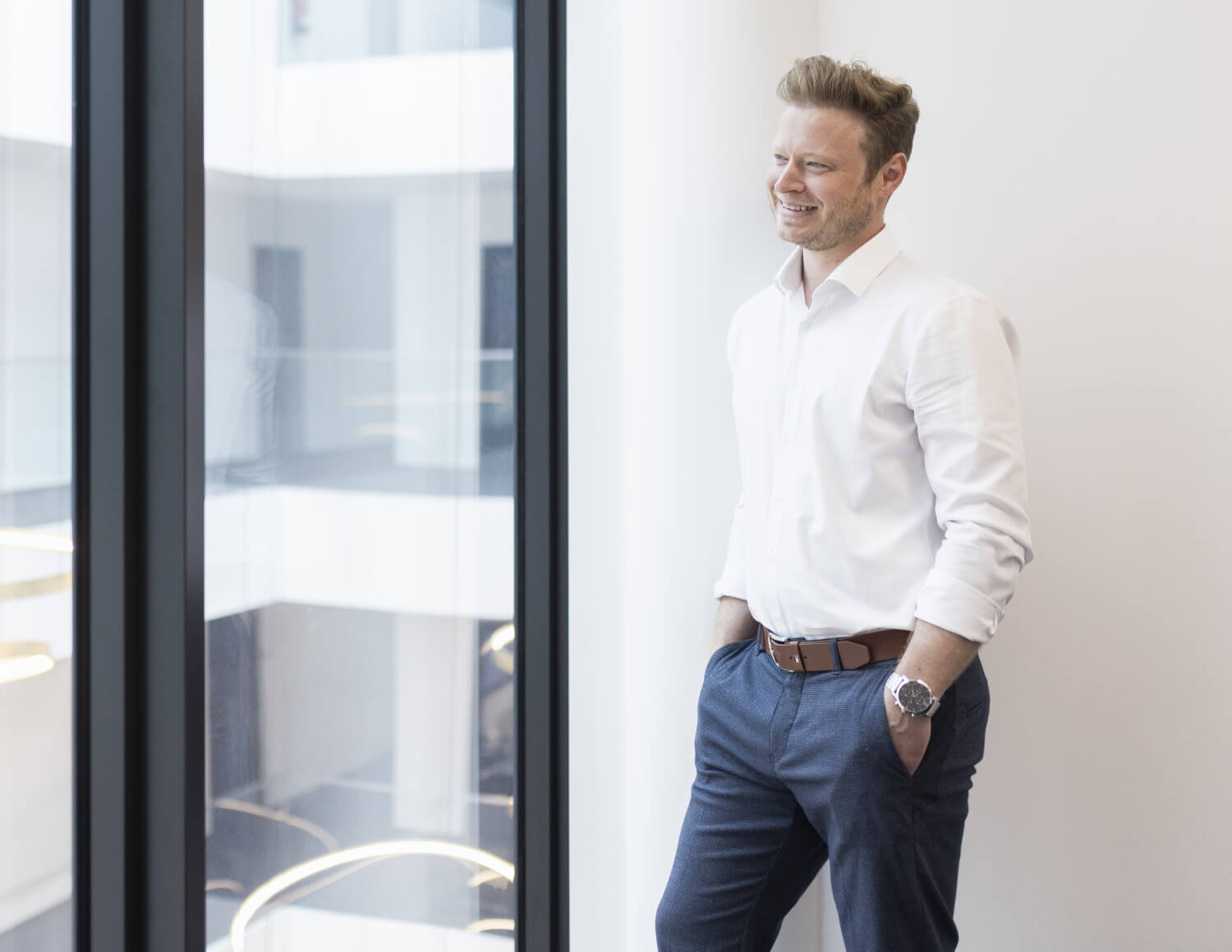 Businessman in a white shirt looks thoughtfully out of the window.