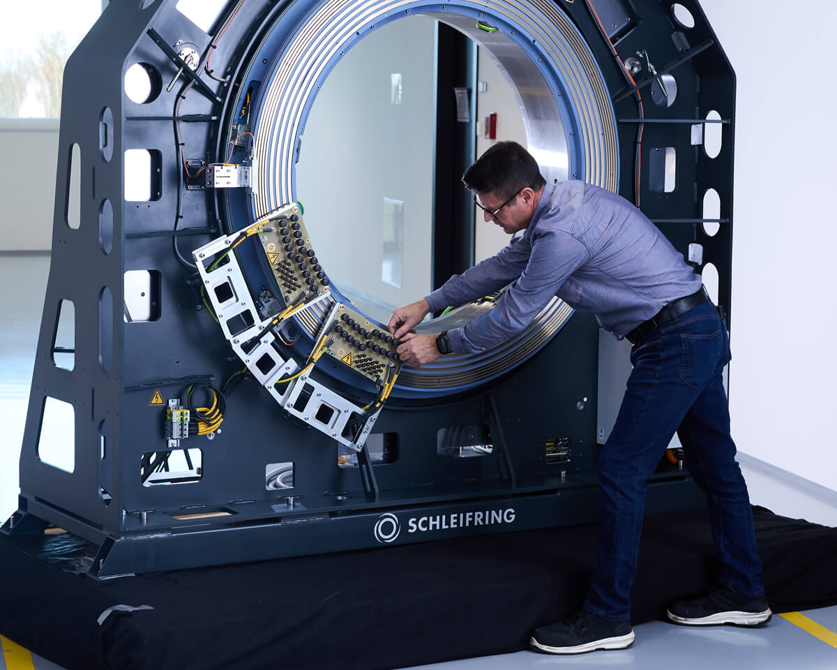 Technician working on a large-format CT slip ring in the test or assembly area.