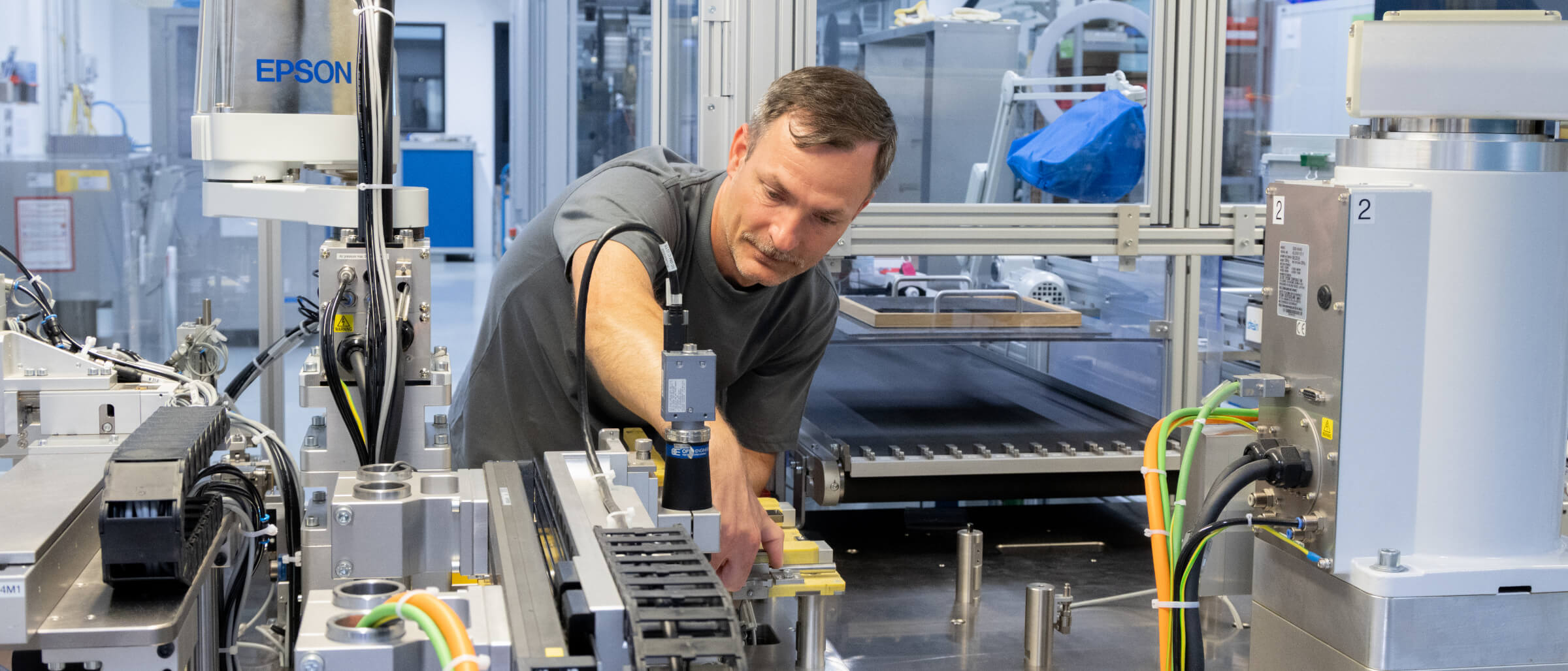 Employee operates a modern industrial system with automated manufacturing components.