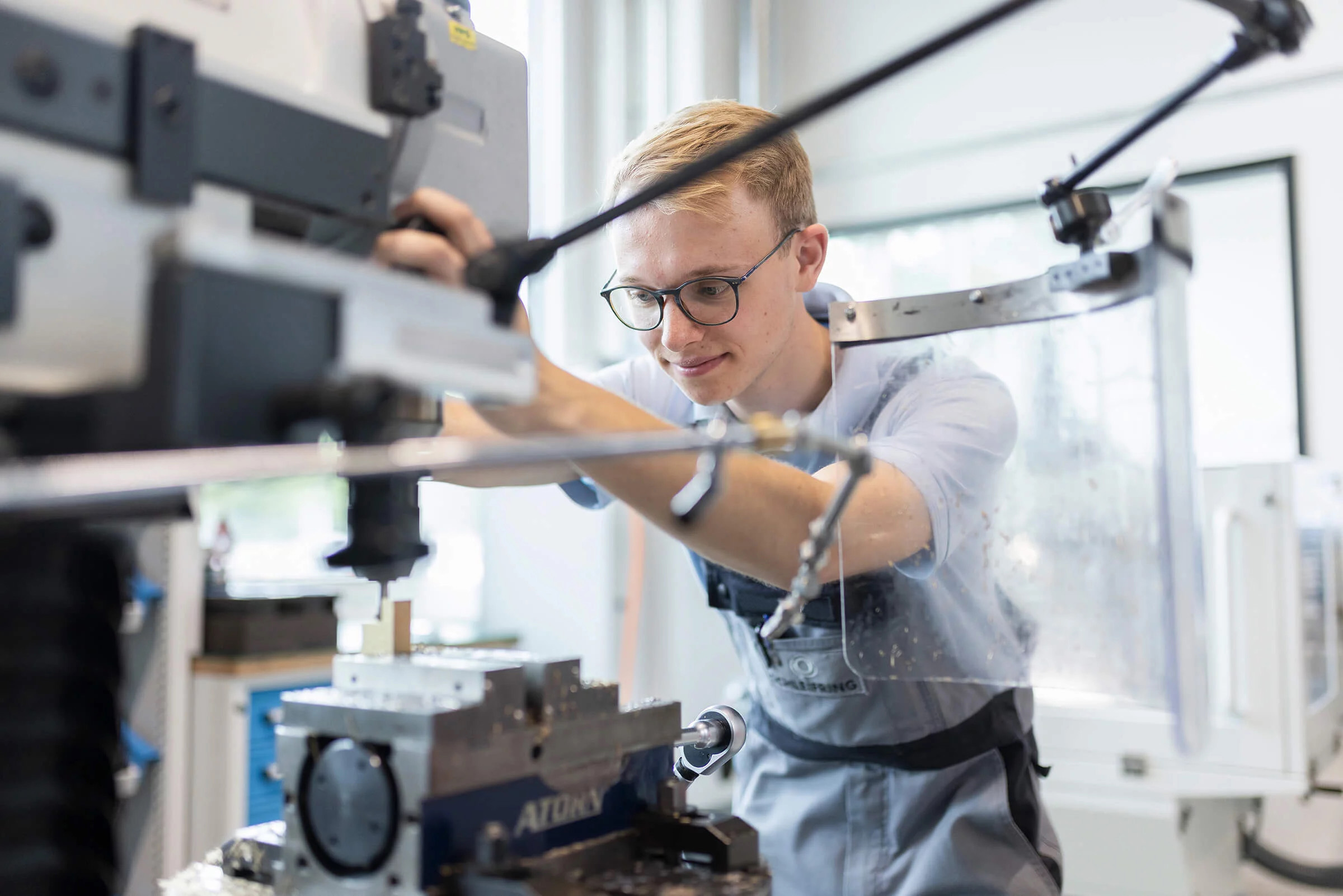 A trainee operates a lathe.