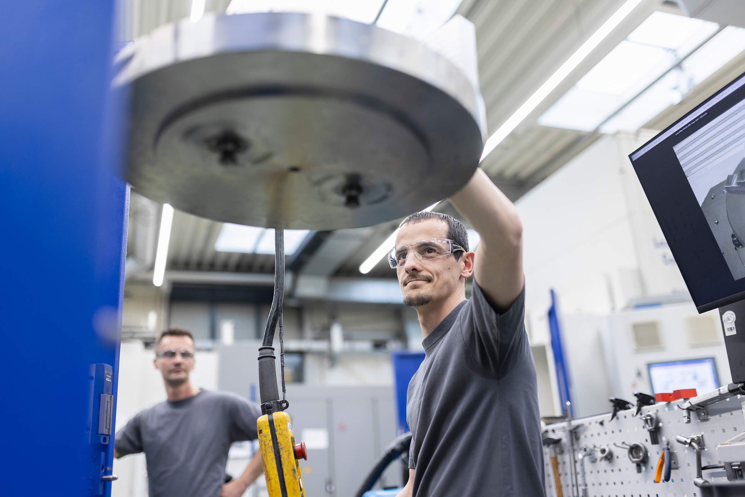 A SCHLEIFRING employee operates an industrial machine in manufacturing.