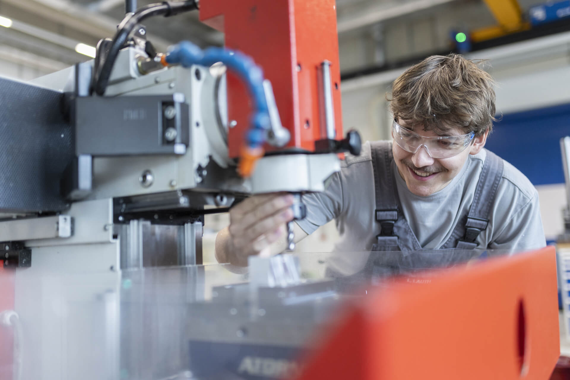 Trainee works with concentration at a CNC machine and is wearing safety goggles.