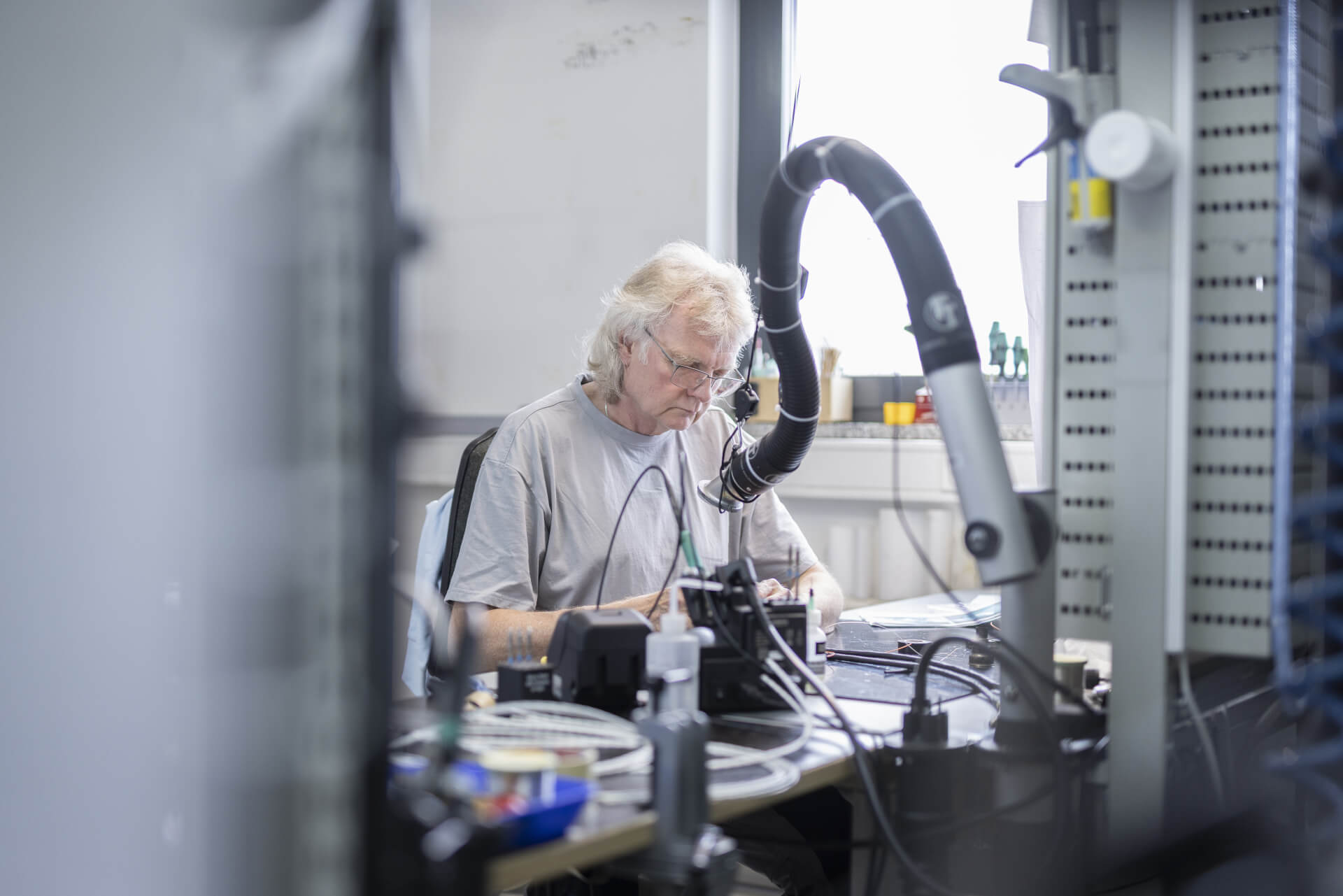 Electronics technician performs soldering work at a specialized workstation.