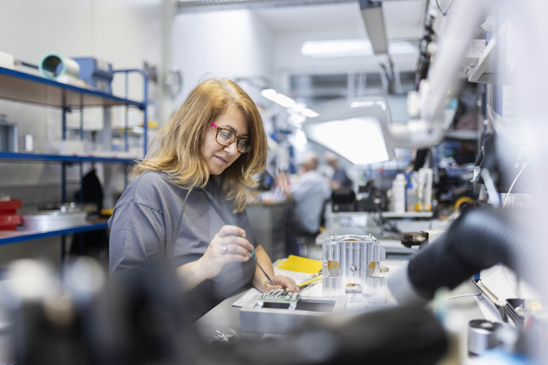 Employee works concentratedly on electronic components in assembly.