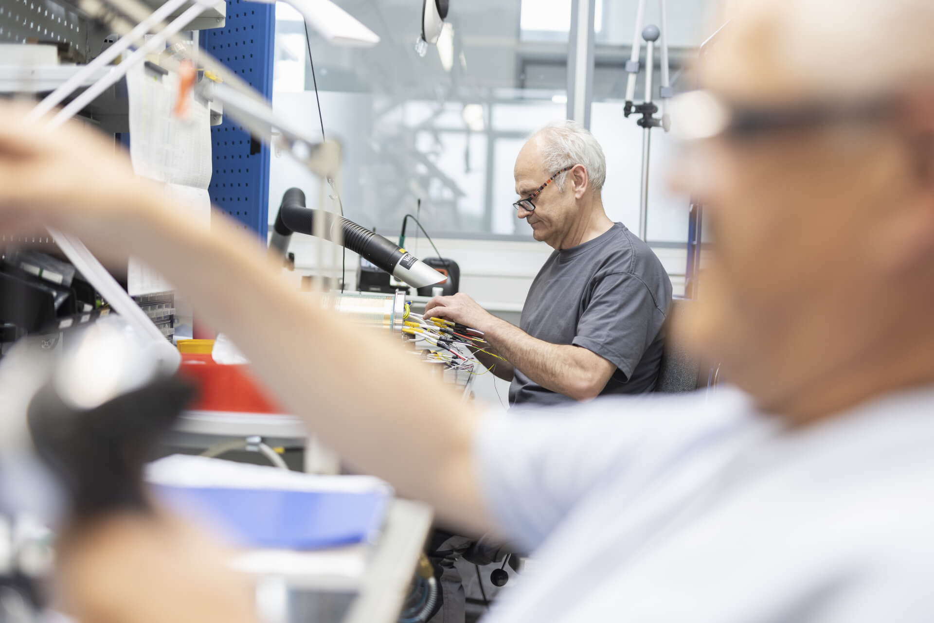 Two employees work at a workstation for assembling electronic components.
