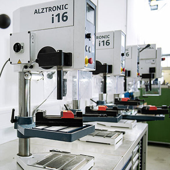 Row of modern drilling machines in a workshop.