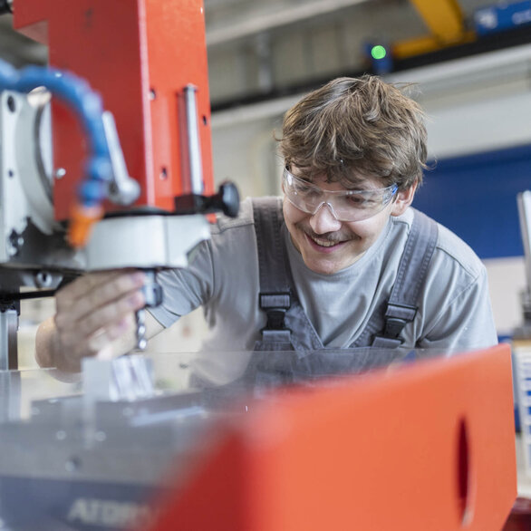 A SCHLEIFRING machining technician inspects an industrial drilling machine.