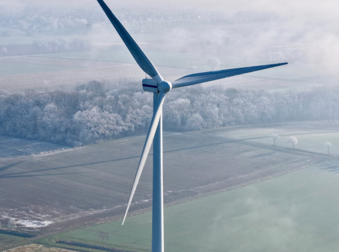 Wind turbine in a field from a bird's-eye view on a foggy morning.