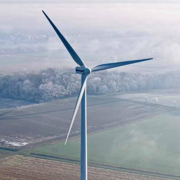 Wind turbine in a field from a bird's eye view on a foggy morning