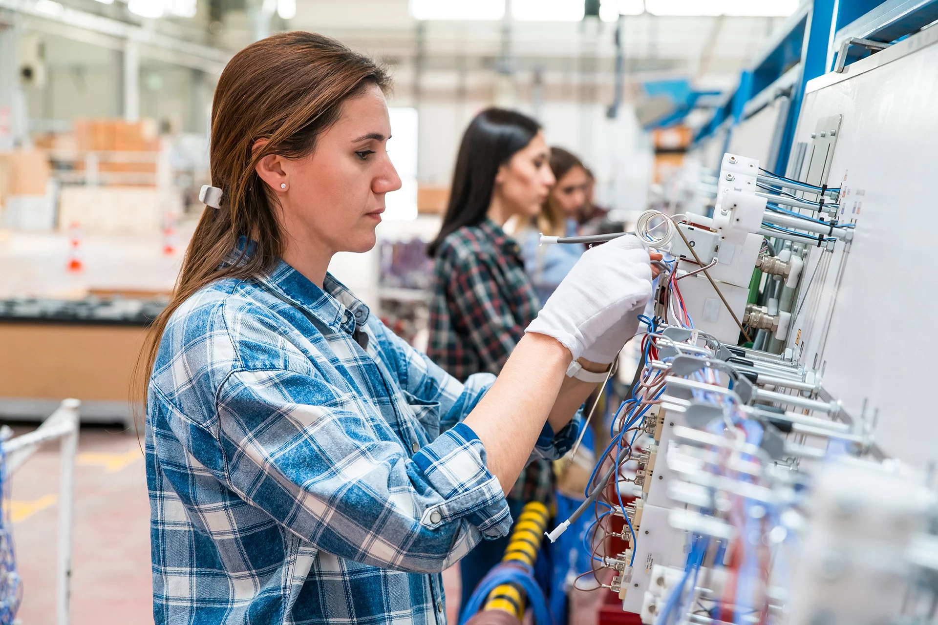 Female worker assembling components on a production line in a factory.