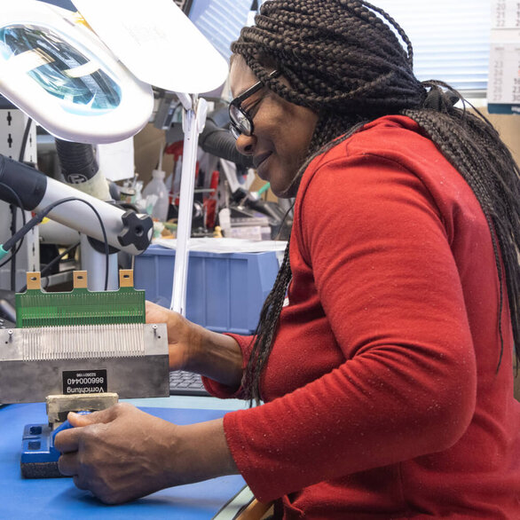 Employee performing precise assembly of electronic components in manufacturing at SCHLEIFRING.