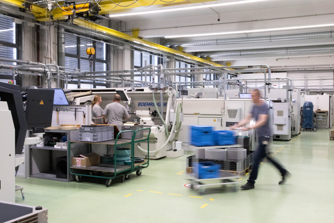 Employees working in a modern industrial production facility with automated machinery.