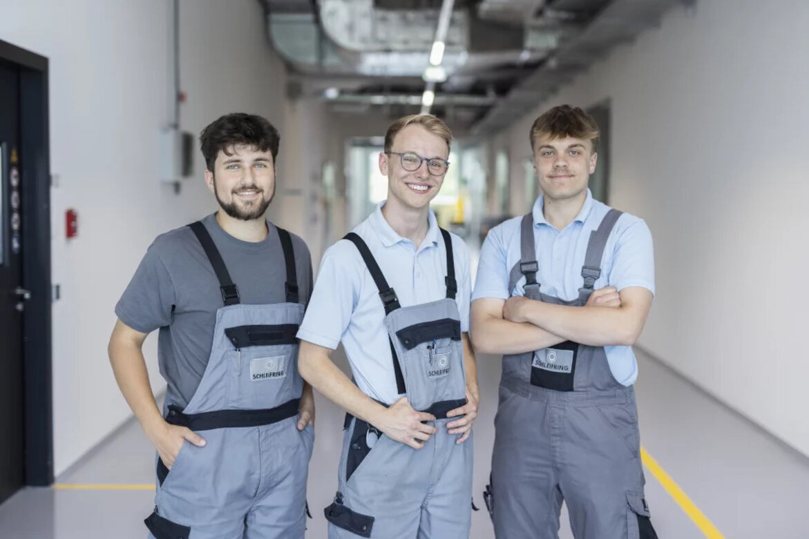 Three SCHLEIFRING trainees are looking at the camera.