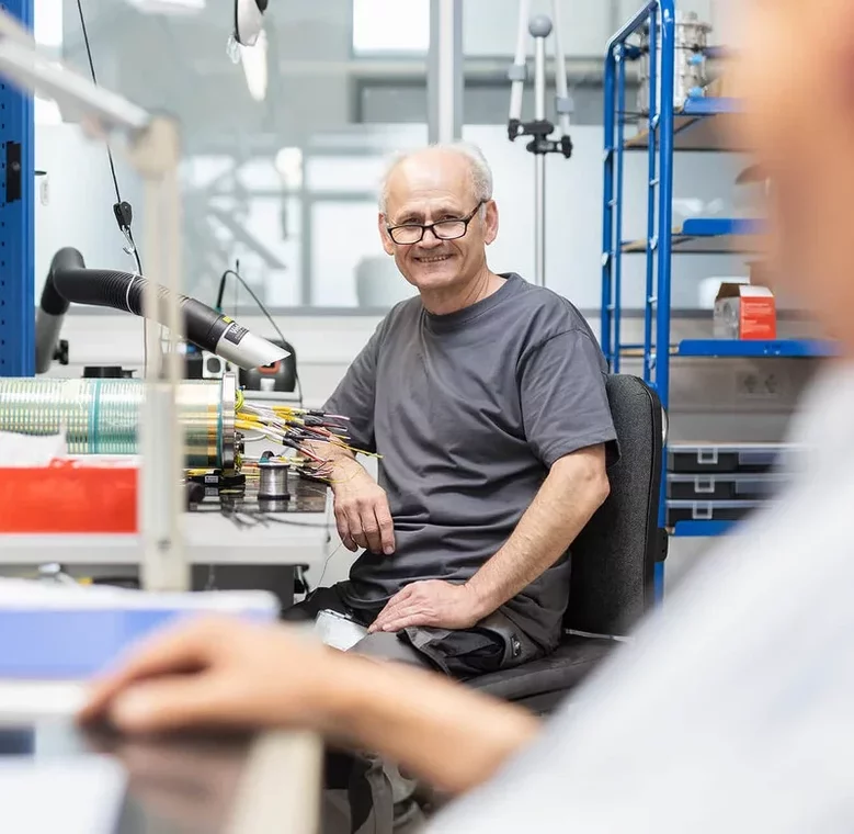 Employee sits smiling at his workplace in electronics production.