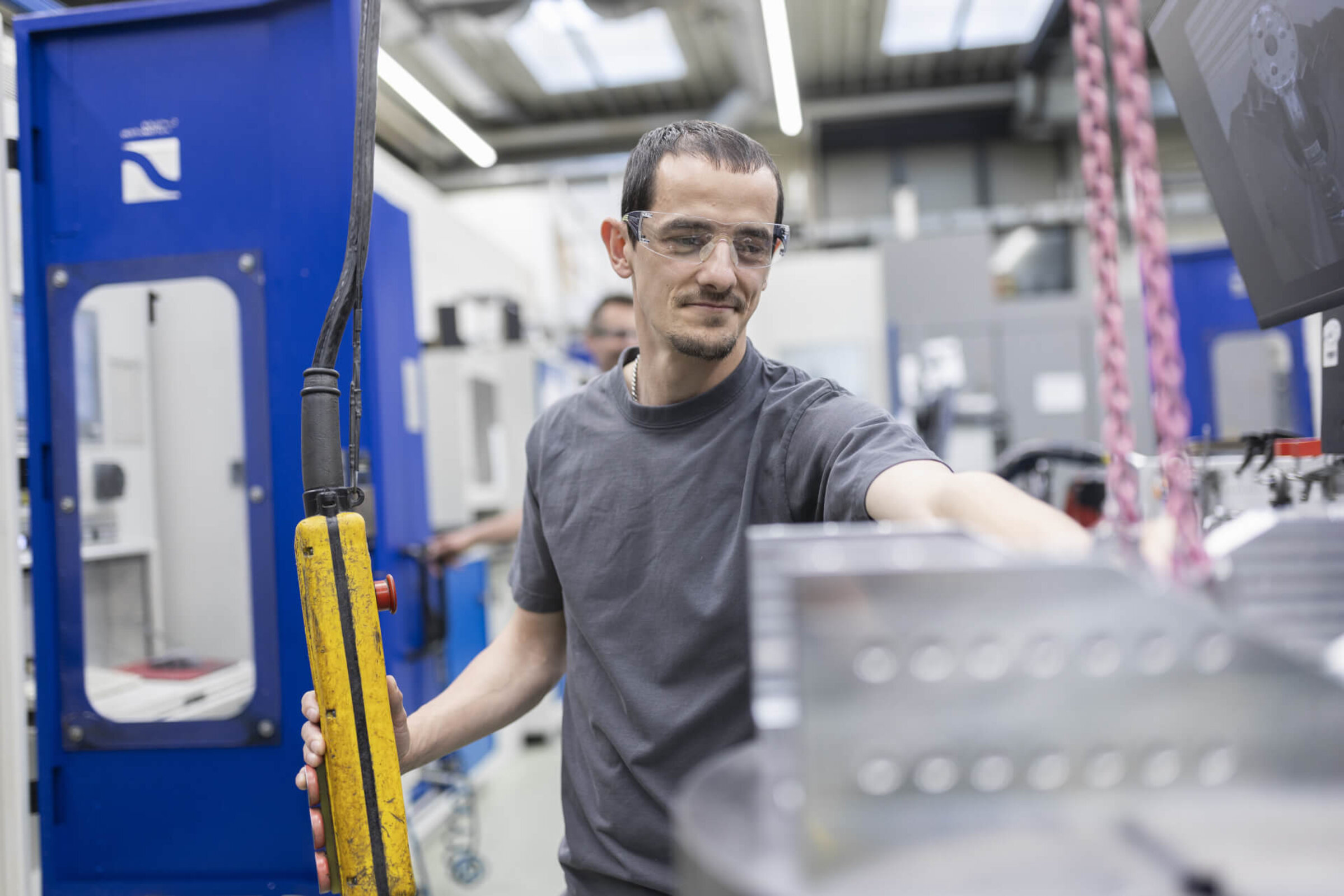 Employee concentrates on operating a crane in the production hall.