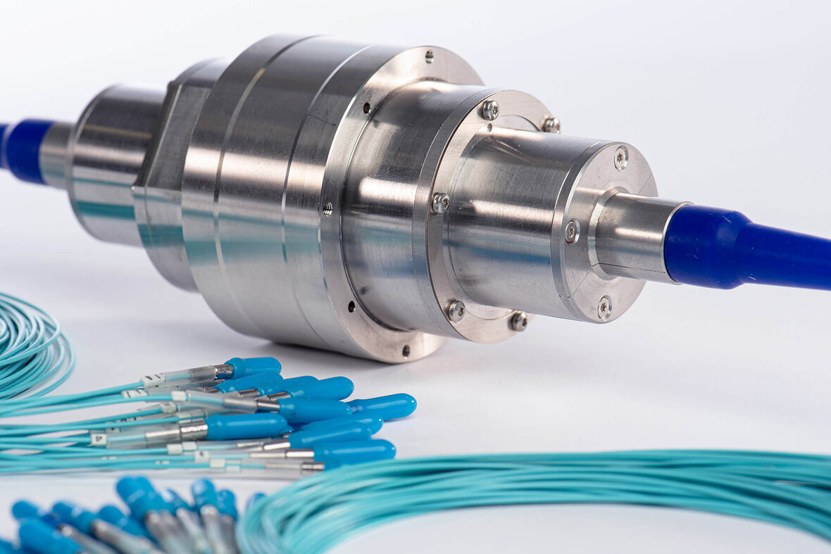 Fiber-optic rotary joint (FORJ) with green optical fiber for high-speed data transmission.