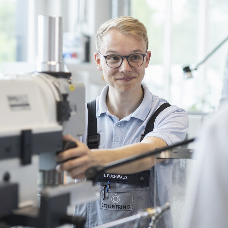 Trainee operates a lathe with concentration in the training center.