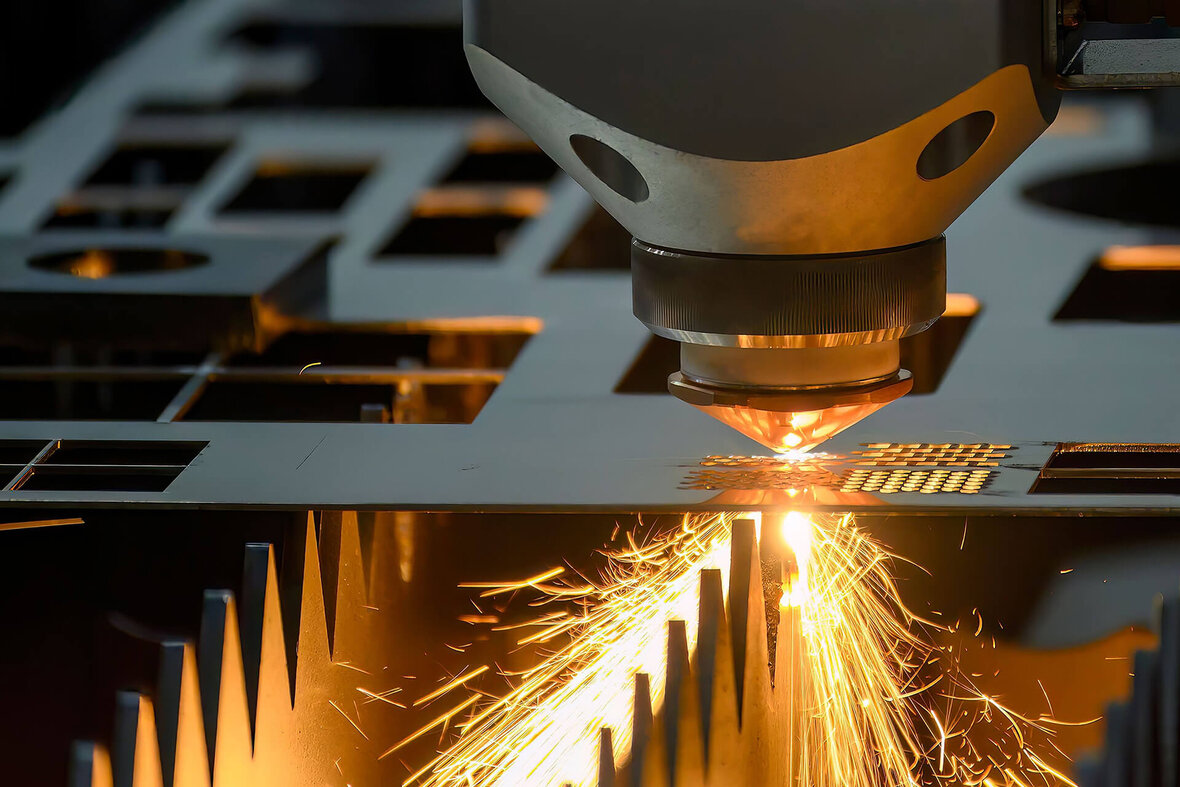 Laser cutting machine precisely cutting a metal plate with visible sparks.